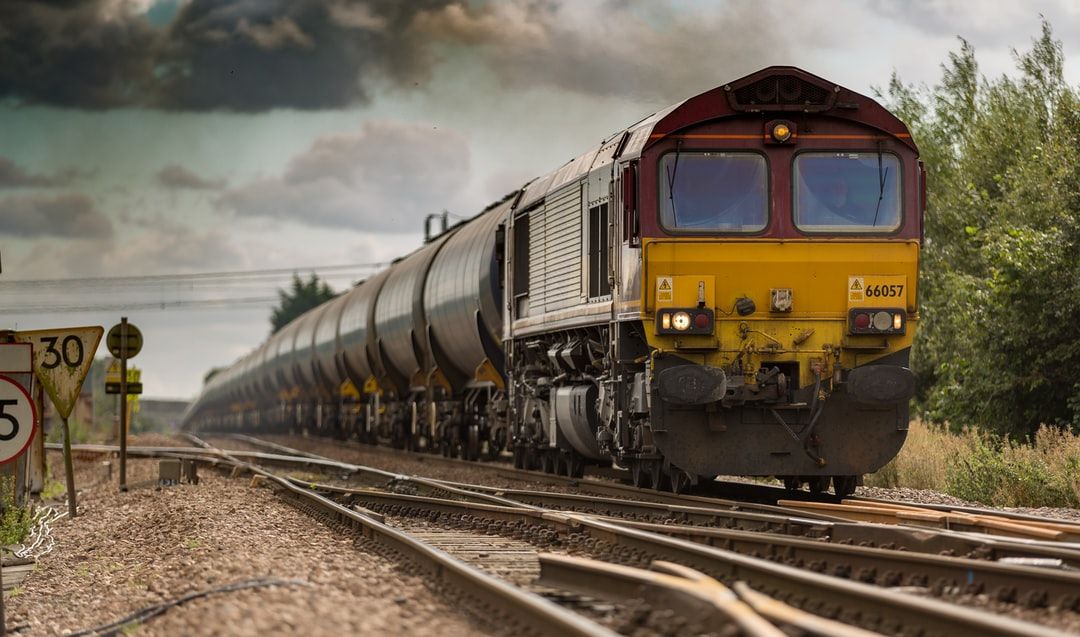 A moving freight train on railroad tracks on a cloudy day